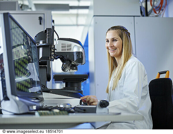 Happy technician working on computer at E-Laboratory