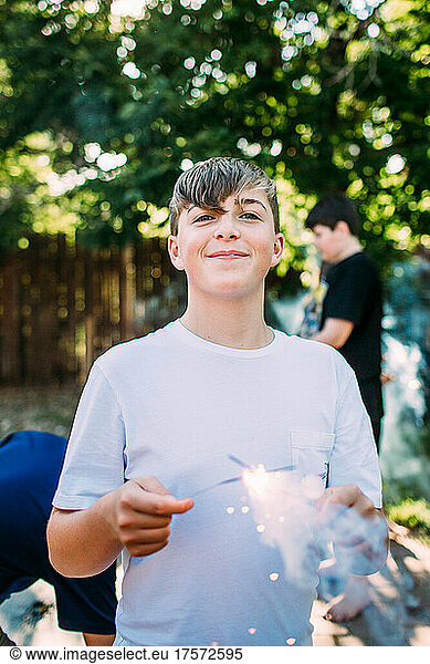 Happy teen boy playing with a sparkler outside