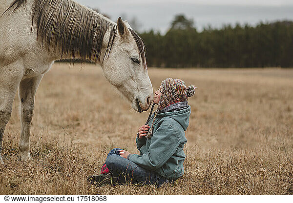 Happy teen girl kissing horse on nose