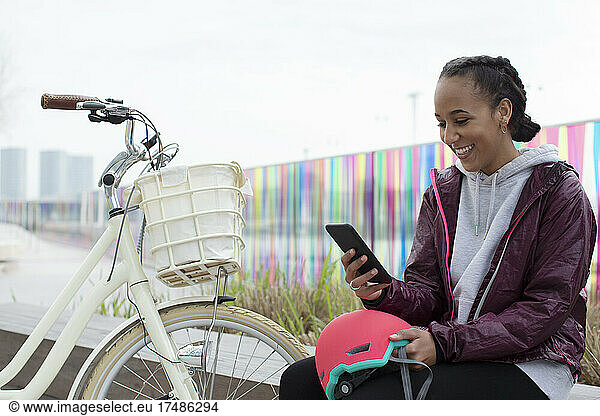 Happy teen girl with bicycle using smart phone