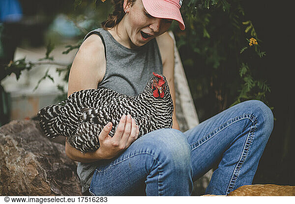 Happy teen girl with chicken laying on her lap