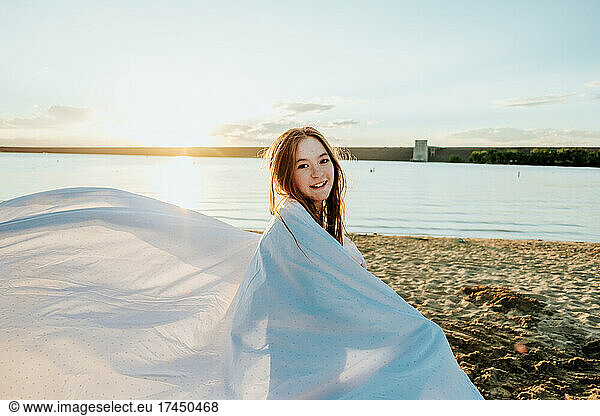Happy Teen Girl Wrapped in sheet at beach