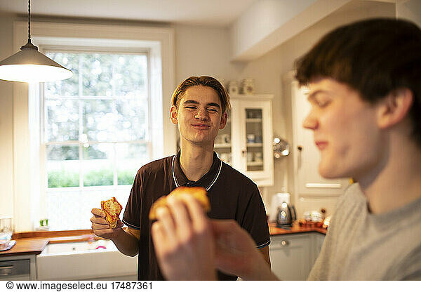 Happy teenage boys eating pizza in kitchen