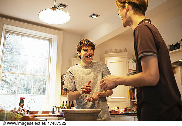 Happy teenage boys making hamburger patties in kitchen