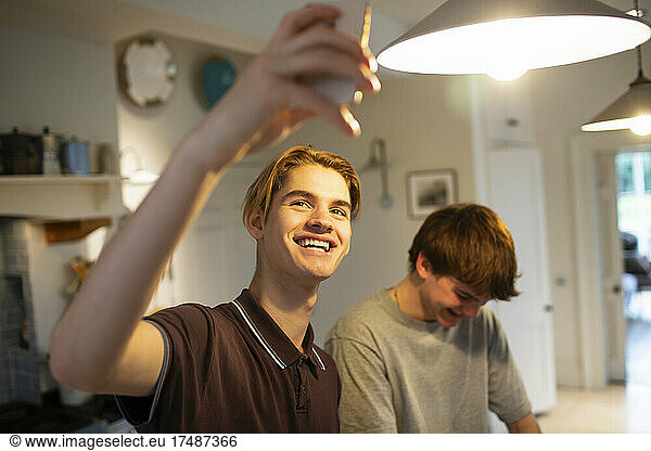 Happy teenage boys taking selfie in kitchen