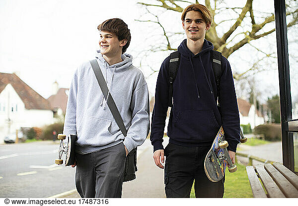 Happy teenage boys with skateboards on sidewalk