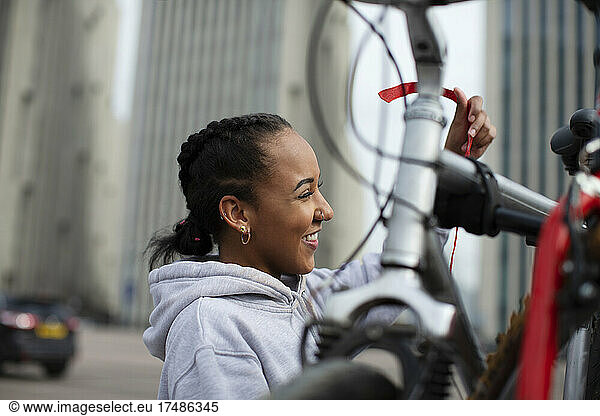 Happy teenage girl lifting bicycle