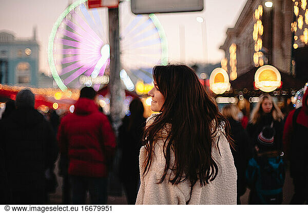 Happy teenage girl walking in Christmas market in evening city