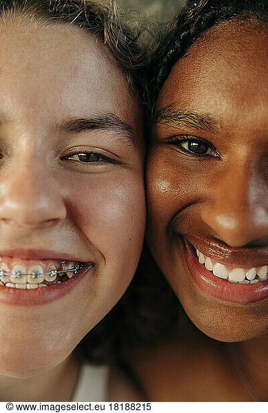Happy teenage girl wearing braces by female friend