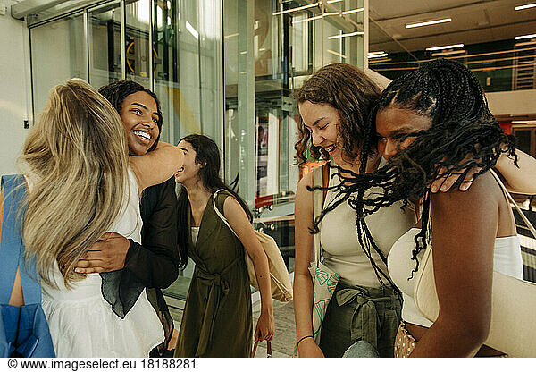 Happy teenage girls greeting each other while enjoying in mall