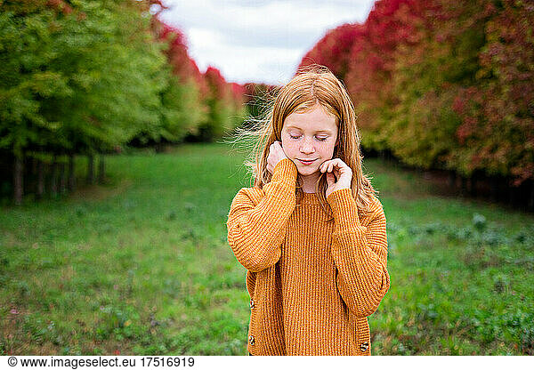 Happy tween girl surrounded by fall color trees.