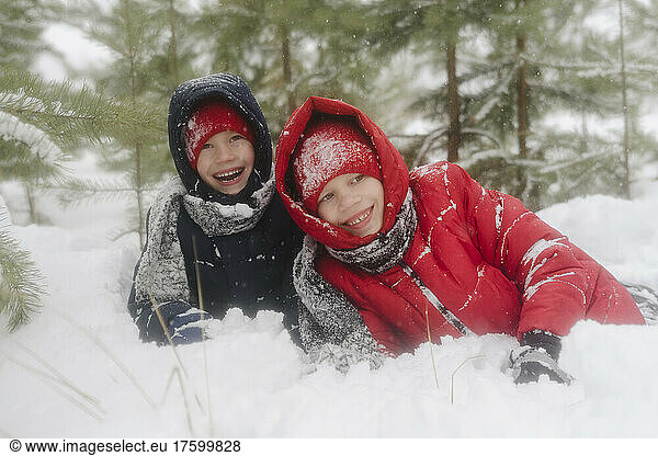 Happy twin brothers enjoying winter in snow forest