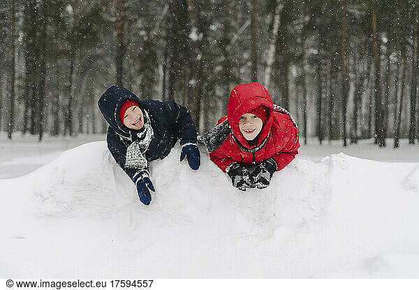 Happy twin brothers playing in snowy forest