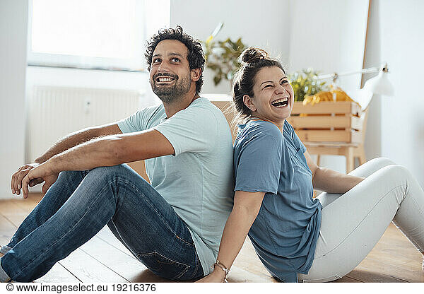 Happy woman and man sitting on floor at home