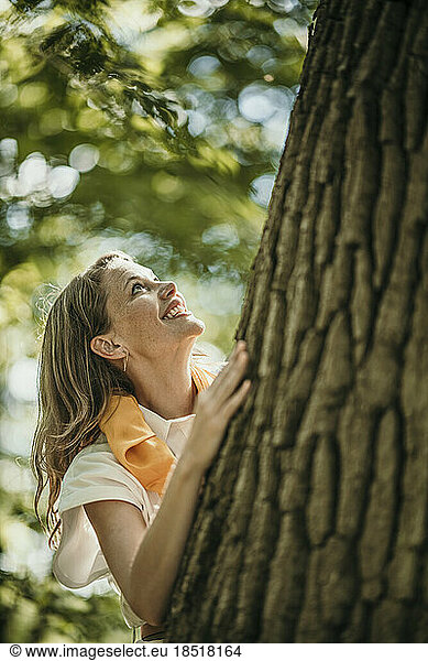Happy woman by tree in forest