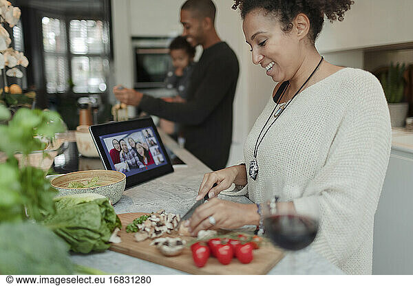 Happy woman cooking and video chatting at digital tablet in kitchen