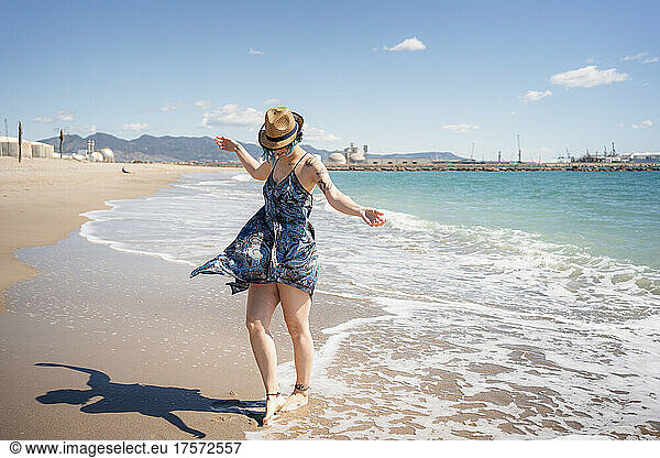 Happy woman dancing free on the beach with hat