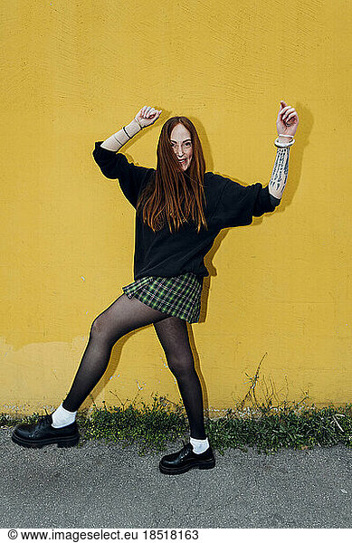 Happy woman dancing in front of wall