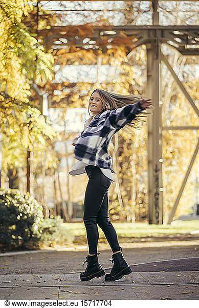 Happy woman dancing outdoors in autumn