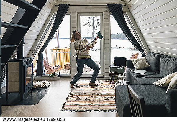 Happy woman dancing with broom at home