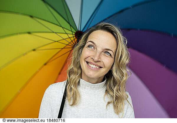 Happy woman day dreaming with multi colored umbrella