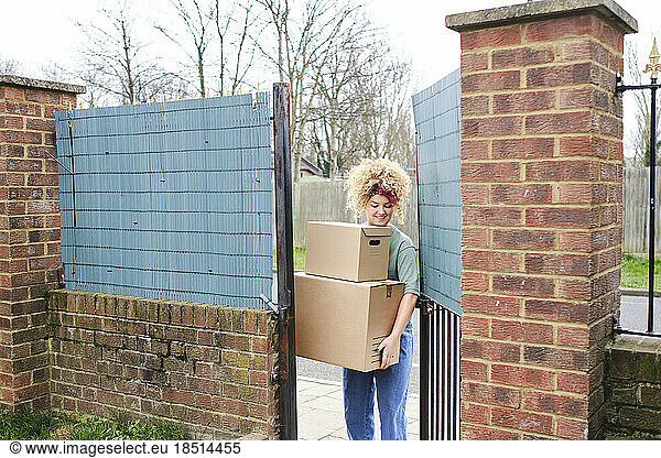 Happy woman delivering packages entering through gate
