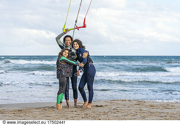Happy woman embracing daughters holding handle at beach