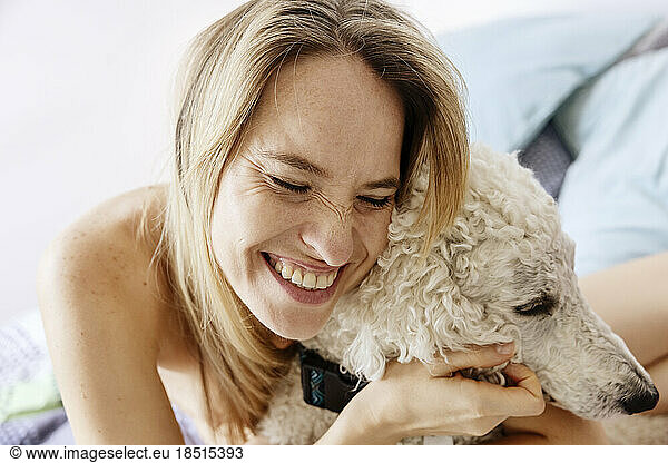 Happy woman embracing dog at home