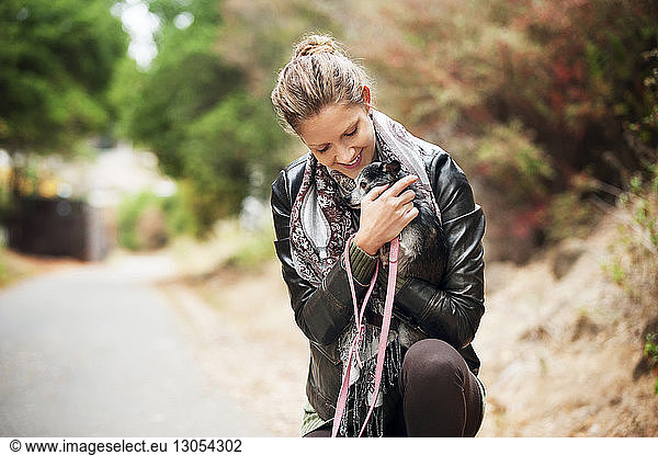 Happy woman embracing dog on road