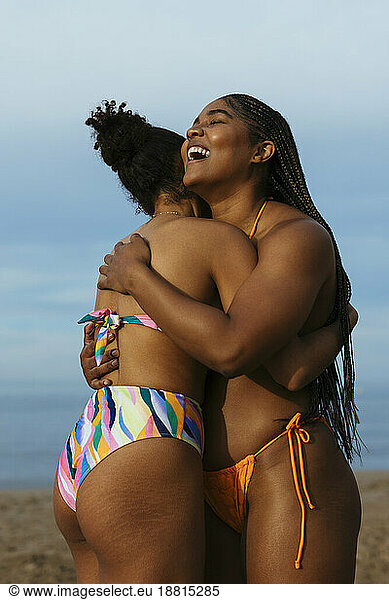 Happy woman embracing friend at beach