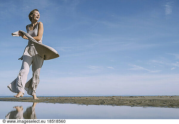 Happy woman enjoying at beach in front of sky