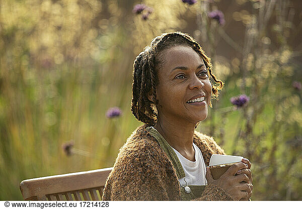 Happy woman enjoying coffee in sunny garden