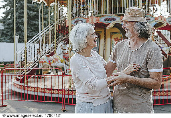 Happy woman enjoying with man in front of carousel