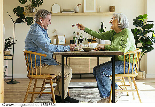 Happy woman feeding senior man at home