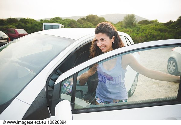 Happy woman getting into car at the coast
