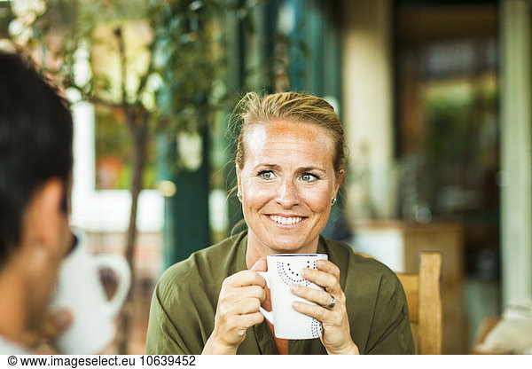 Happy woman holding coffee cup while looking at man