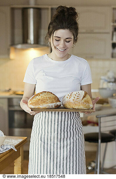 Happy woman holding freshly baked loafs of bread