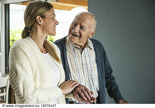 Happy woman holding hands and spending time with father at home