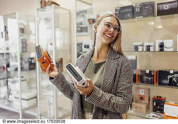Happy woman holding instant cameras in store
