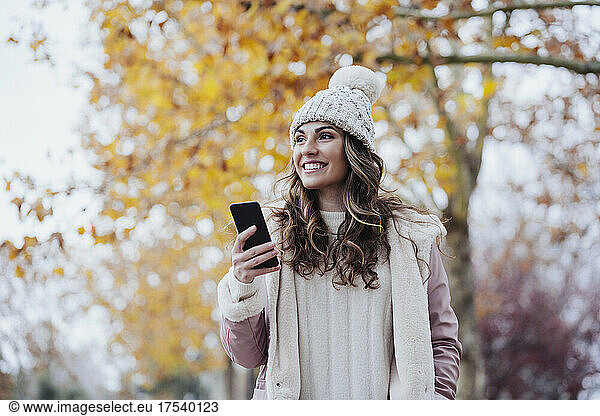 Happy woman holding smart phone at park