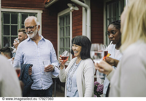 Happy woman holding wineglass with family during social gathering