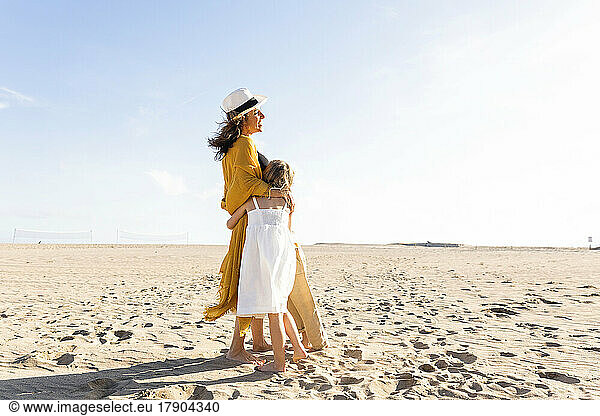 Happy woman hugging daughter and son at beach on sunny day