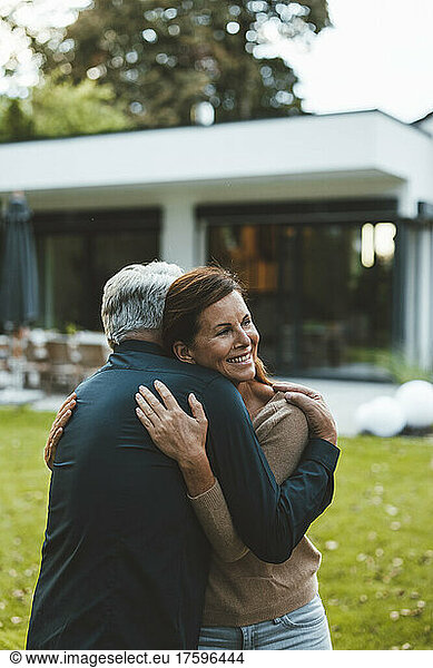 Happy woman hugging man at backyard