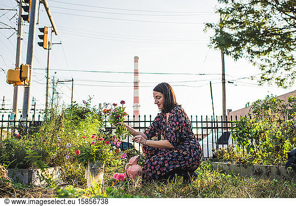happy woman in an urban garden picking flowers