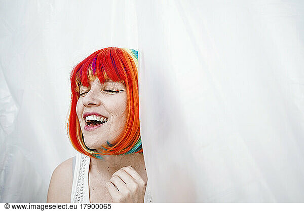 Happy woman in colorful dyed hair amidst plastic foil