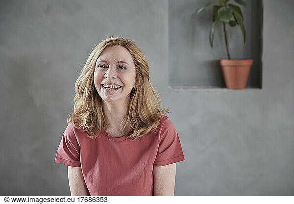 Happy woman in front of gray wall