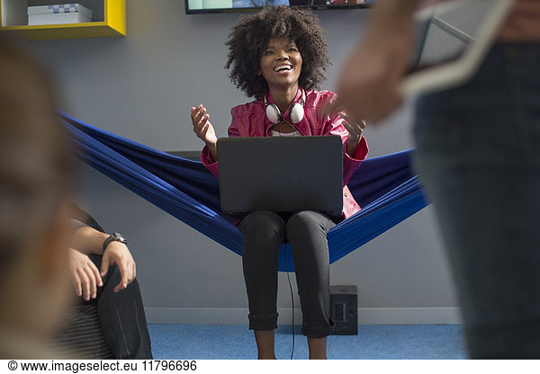 Happy woman in hammock with laptop