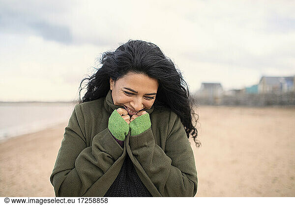 Happy woman in winter coat on beach