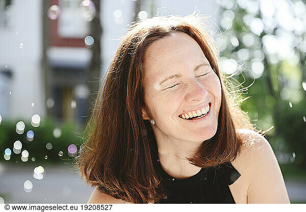 Happy woman laughing with eyes closed at sunny day