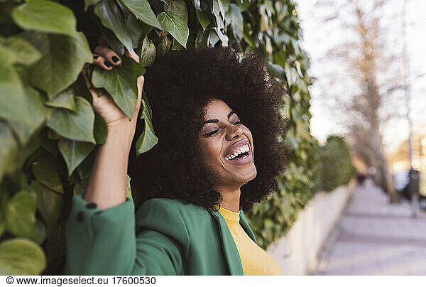Happy woman leaning on ivy wall
